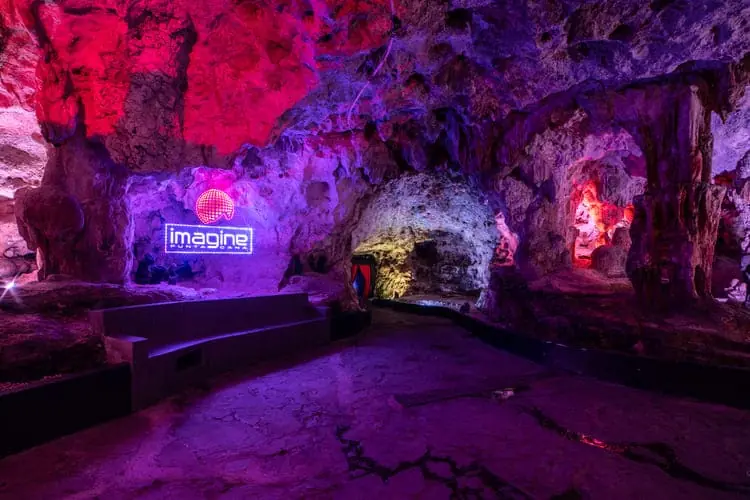 grotto inside Imagine Punta Cana cave nightclub with neon logo illuminated in purple lighting
