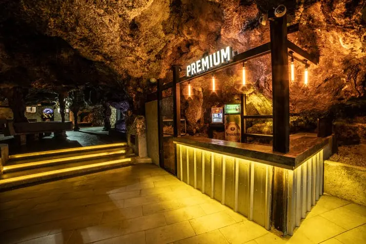 premium bar inside the Imagine Punta Cana cave nightclub with elegant golden lighting
