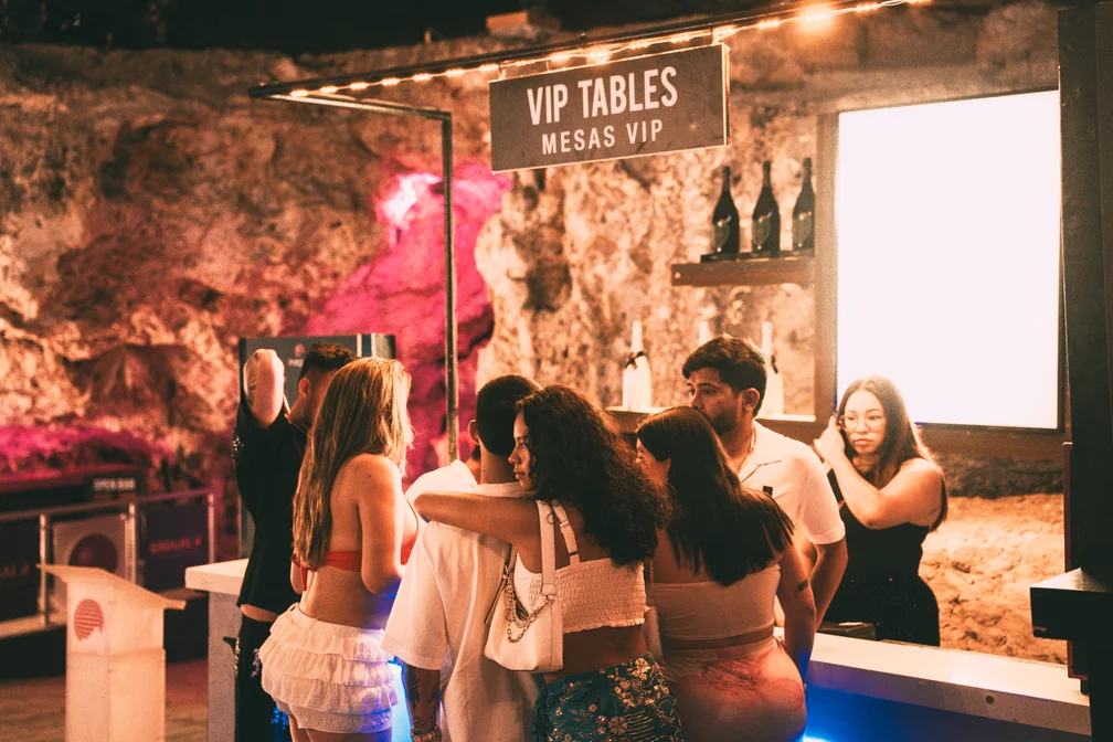 Group of young people at the VIP table bar at Imagine Punta Cana with "VIP Tables" sign
