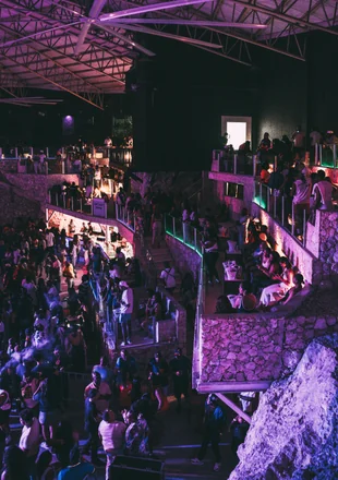 Ambiente de Imagine Punta Cana visto desde arriba: múltiples niveles, público bailando e iluminación morada en la cueva natural