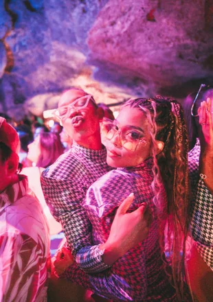 Pareja disfrutando la noche en Imagine Punta Cana, con máscara neón e iluminación rosa dentro de la cueva